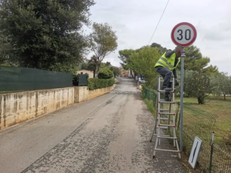 Djelatnik tvrtke LIČILAC d.o.o. postavlja prometni znak ograničenja brzine na 30 km na sat u naselju Banjole.