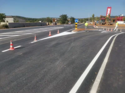 Horizontalna signalizacija s usmjernim strelicama i znakom obveznog smjera uz radnike na terenu.