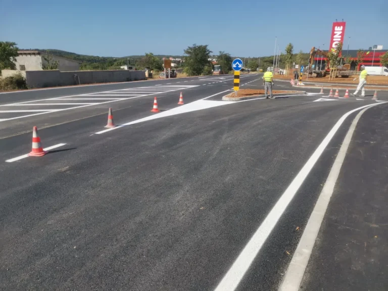 Horizontalna signalizacija s usmjernim strelicama i znakom obveznog smjera uz radnike na terenu.