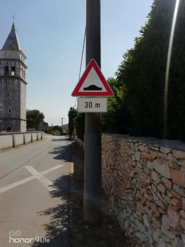 Znak upozorenja na ležećeg policajca s dopunskom pločom udaljenosti