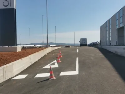 Bijela zaustavna linija i prometni otok iscrtani ispred ulaza u poslovnu zonu