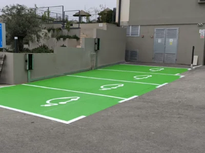Zelena parkirna mjesta s bijelim piktogramima za punjenje električnih vozila.