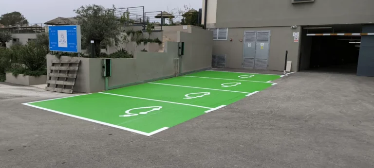 Zelena parkirna mjesta s bijelim piktogramima za punjenje električnih vozila.