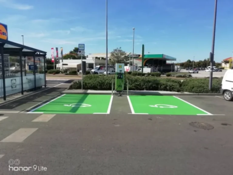 Parkirališna mjesta obojana u zeleno s bijelim oznakama za punionicu električnih vozila.