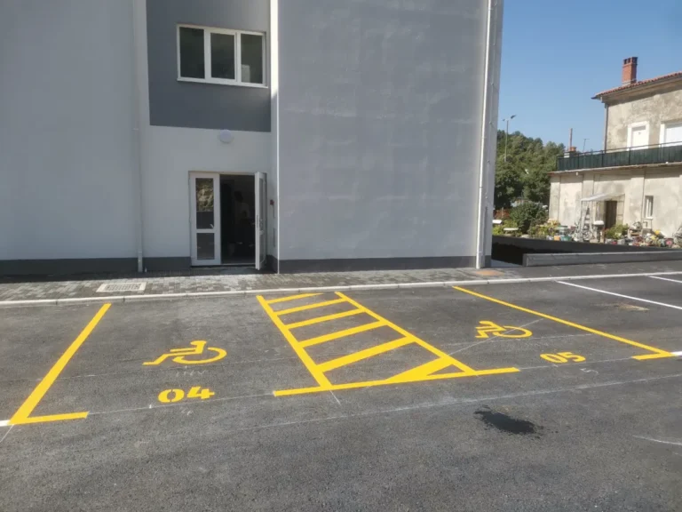 Žutom bojom jasno označena parkirališna mjesta za osobe s invaliditetom ispred ulaza u zgradu.