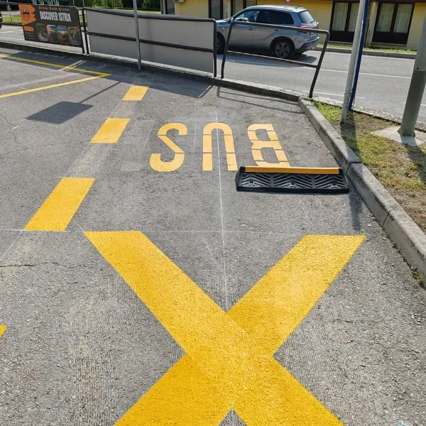 Žute oznake za autobusno stajalište i gumeni graničnik na asfaltu u Motovunu