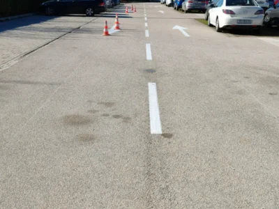 Dugačka isprekidana bijela linija i strelice za usmjeravanje prometa na asfaltu