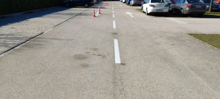 Dugačka isprekidana bijela linija i strelice za usmjeravanje prometa na asfaltu
