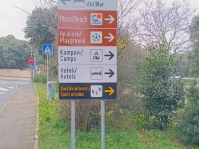 Detaljan prikaz vertikalne signalizacije uz cestu koja usmjerava prema lokalnim plažama i crkvi.