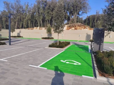 Zeleno obojena parkirna mjesta za električna vozila s bijelim simbolom automobila i punjača.