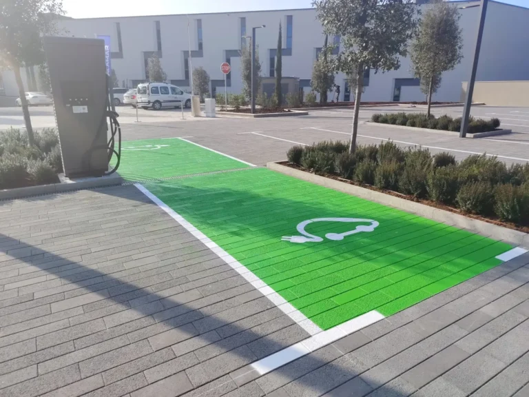 Detaljan prikaz jarko zelenog parkirališnog mjesta s piktogramom električnog vozila uz stanicu za punjenje.