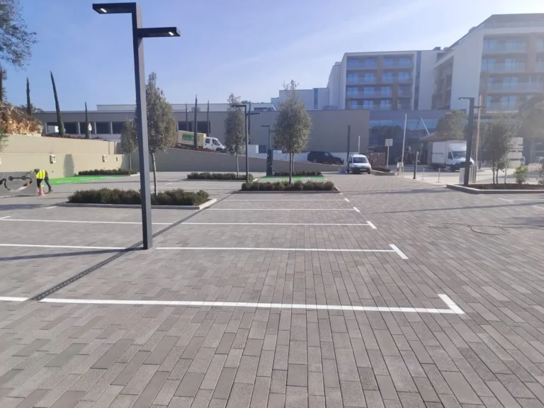Iscrtane bijele linije za parkirna mjesta na sivom opločniku ispred modernog hotela.