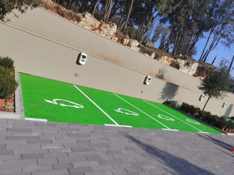 Tri parkirna mjesta obojana u zeleno s bijelim oznakama za električne automobile u Poreču.