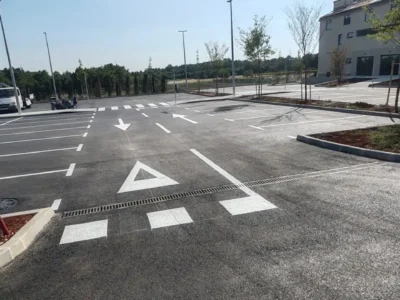 Prostrano parkiralište s precizno iscrtanim bijelim linijama za parkirna mjesta i pješačkim prijelazom