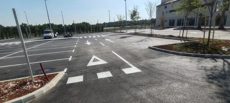 Prostrano parkiralište s precizno iscrtanim bijelim linijama za parkirna mjesta i pješačkim prijelazom