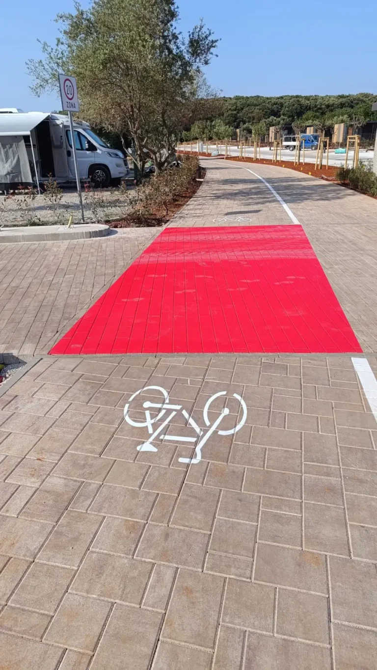 Jasno iscrtan biciklistički prijelaz s bijelim simbolom bicikla na popločanoj stazi