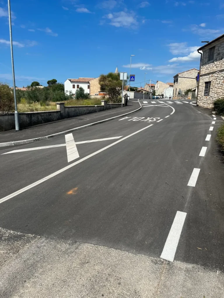 Veliki natpis škola iscrtan na kolniku kao dio horizontalne signalizacije za smirivanje prometa.