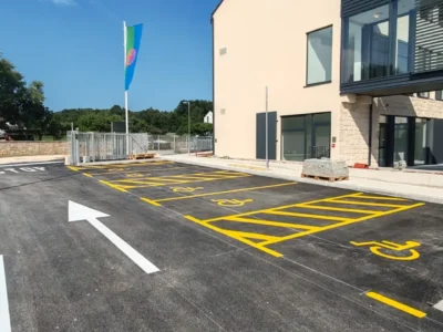Žuta parkirna mjesta za osobe s invaliditetom i usmjeravajuće strelice na novom asfaltu