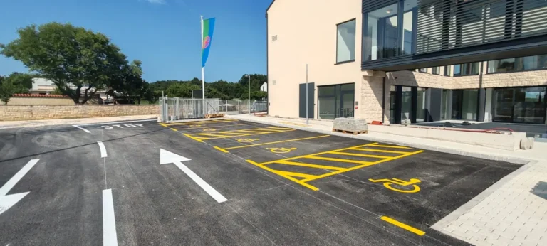 Žuta parkirna mjesta za osobe s invaliditetom i usmjeravajuće strelice na novom asfaltu