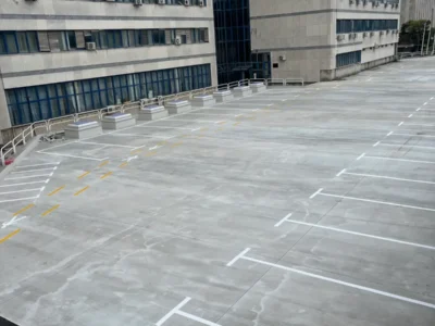 Široki prikaz betonskog platoa s precizno izvučenim bijelim parkirnim linijama i žutim pješačkim oznakama