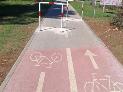 Pocinčane barijere s reflektirajućim trakama na crveno označenoj biciklističkoj stazi u blizini šume.